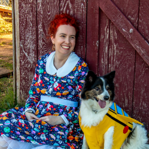 Me, dressed as Ms Frizzle with a space-themed dress and bright red hair, sitting next to Beau, a black and white border collie mix dressed as the Magic School Bus